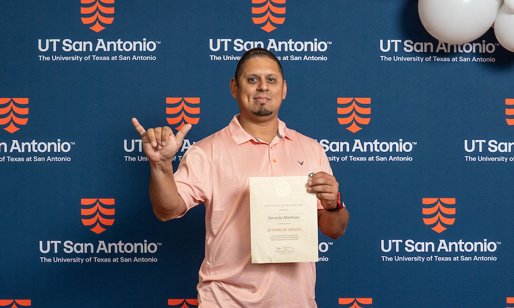 Geraldo holds up his certificate honoring 20 years of service